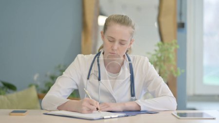 Photo for Writing Female Doctor Working on Medical Report in Clinic - Royalty Free Image