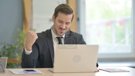 Téléchargez les photos : Homme d'affaires excité célébrant le succès sur ordinateur portable - en image libre de droit