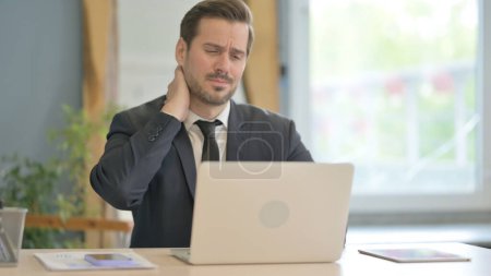 Téléchargez les photos : Homme d'affaires avec douleur au cou travaillant sur ordinateur portable - en image libre de droit