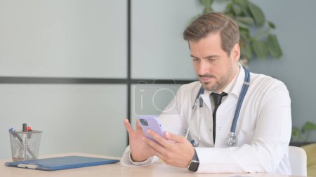 Photo for Male Doctor Using Smartphone in Clinic - Royalty Free Image