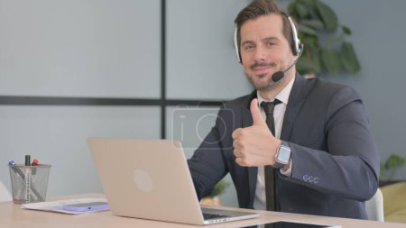 Photo for Thumbs Up by Young Man with Headset in Call Center - Royalty Free Image