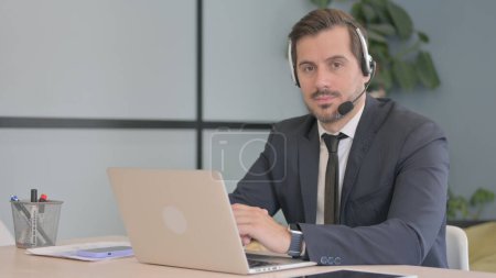 Photo for Businessman with Headset Looking toward Camera in Call Center - Royalty Free Image