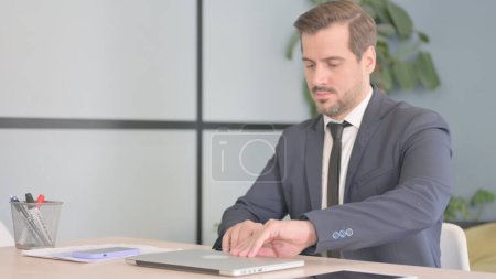 Téléchargez les photos : Un homme d'affaires arrive au bureau et commence à travailler sur un ordinateur portable - en image libre de droit