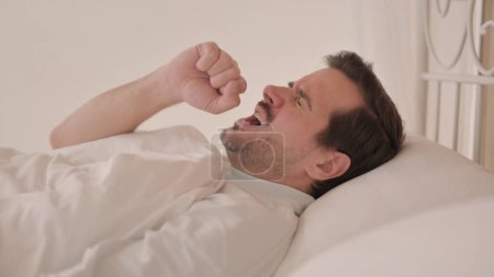 Foto de Vista lateral de un hombre joven tosiendo en la cama - Imagen libre de derechos
