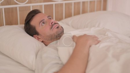 Téléchargez les photos : Brainstorming Jeune homme couché au lit - en image libre de droit