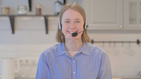 Téléchargez les photos : Jeune femme avec casque souriant à la caméra dans le centre d'appels - en image libre de droit