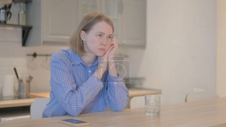 Foto de Mujer joven pensativa pensando mientras está sentada en casa - Imagen libre de derechos