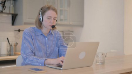Téléchargez les photos : Jeune femme avec casque de travail sur ordinateur portable dans le centre d'appels - en image libre de droit