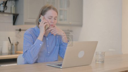 Téléchargez les photos : Jeune femme parlant au téléphone au travail - en image libre de droit