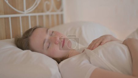 Foto de Vista lateral de una joven cansada acostada en la cama para dormir - Imagen libre de derechos