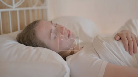 Téléchargez les photos : Vue latérale de la jeune femme dormant au lit - en image libre de droit