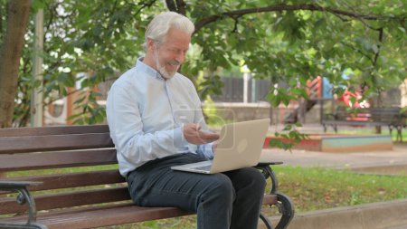 Foto de Chat de vídeo en línea por el anciano mayor en el ordenador portátil al aire libre - Imagen libre de derechos