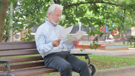 Foto de Anciano mayor leyendo documentos mientras está sentado al aire libre - Imagen libre de derechos