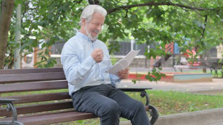 Téléchargez les photos : Vieil homme âgé célébrant tout en lisant des documents en plein air - en image libre de droit