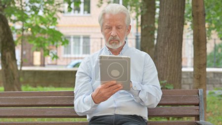 Foto de Anciano mayor usando Tablet mientras está sentado en el parque - Imagen libre de derechos