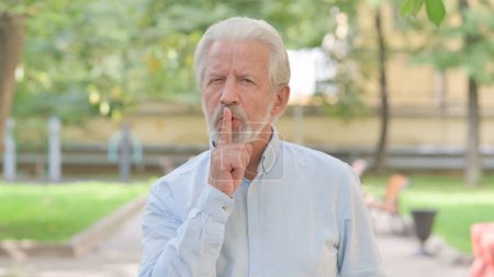 Téléchargez les photos : Portrait extérieur de vieil homme âgé avec doigt sur les lèvres - en image libre de droit