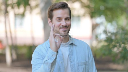 Outdoor Portrait of Young Man Doing Ok Sign