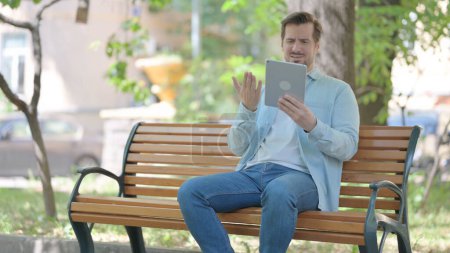 Photo for Young Man Reacting ot Online Loss  on Tablet while Sitting Outdoor - Royalty Free Image