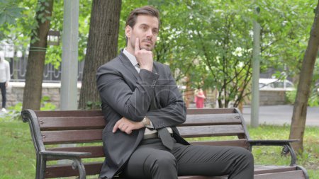 Téléchargez les photos : Brainstorming Jeune homme d'affaires assis en plein air - en image libre de droit