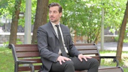 Photo for Angry Young Businessman Sitting Outdoor on Bench - Royalty Free Image