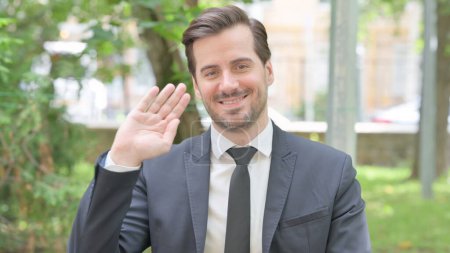 Photo for Outdoor Portrait of Young Businessman Waving to Say Hello - Royalty Free Image