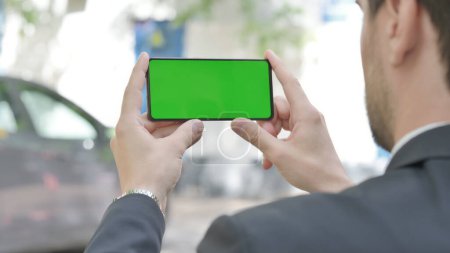 Foto de Joven empresario sosteniendo el teléfono con pantalla verde al aire libre - Imagen libre de derechos