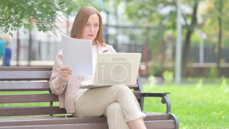 Foto de Anciana mayor se siente molesto mientras lee contrato y el uso de la computadora portátil al aire libre - Imagen libre de derechos