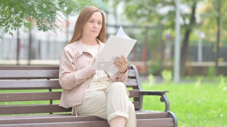 Photo for Senior Old Woman Reading Documents while Sitting Outdoor - Royalty Free Image