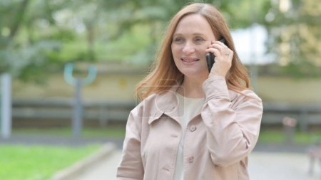 Téléchargez les photos : Vieille femme âgée parlant au téléphone en plein air - en image libre de droit