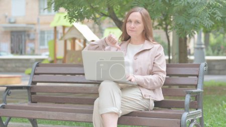 Thumbs Down by Modern Old Woman Using Laptop Outdoor