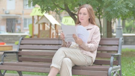 Téléchargez les photos : Moderne vieille femme lecture de documents en plein air - en image libre de droit