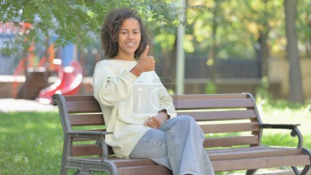 Photo for Thumbs Up by Young African Woman Sitting Outdoor - Royalty Free Image