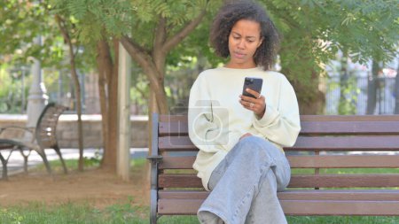 Téléchargez les photos : Casual africaine femme choquée par la perte sur téléphone extérieur - en image libre de droit