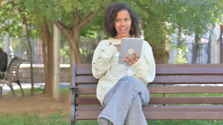 Foto de Casual africana mujer haciendo video chat en la tableta al aire libre - Imagen libre de derechos
