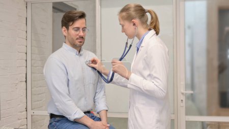 Téléchargez les photos : Médecin féminin écoutant la poitrine du patient à l'aide d'un stéthoscope - en image libre de droit