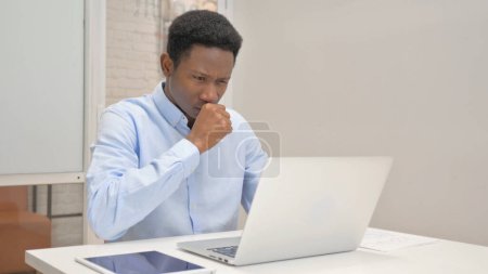 Téléchargez les photos : Toux homme d'affaires africain utilisant un ordinateur portable dans le bureau - en image libre de droit