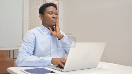 Foto de Empresario africano con dolor de muelas Trabajando en el ordenador portátil en la oficina - Imagen libre de derechos