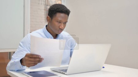 Foto de Empresario africano trabajando en documentos y computadoras portátiles - Imagen libre de derechos
