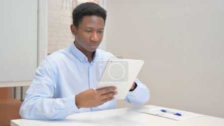 Téléchargez les photos : Homme d'affaires africain utilisant une tablette numérique au bureau - en image libre de droit