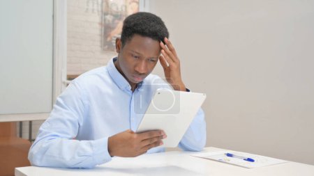 Téléchargez les photos : Homme d'affaires africain avec perte sur tablette au bureau - en image libre de droit