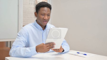 Foto de Empresario africano haciendo video chat en tableta en la oficina - Imagen libre de derechos