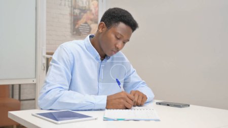 Foto de Empresario africano escribiendo una carta en el cargo - Imagen libre de derechos