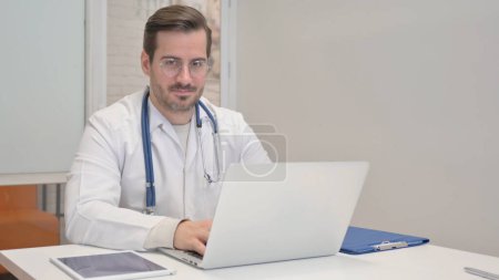 Foto de Pulgares hacia arriba por el médico usando el ordenador portátil en la clínica - Imagen libre de derechos