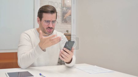 Photo for Middle Aged Man Shocked by Loss on Phone in Office - Royalty Free Image