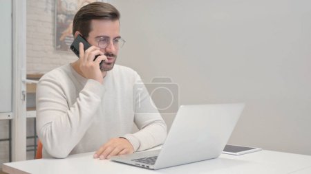 Foto de Hombre de mediana edad hablando por teléfono en el trabajo - Imagen libre de derechos