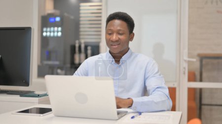 Photo for African Businessman Chatting Online on Laptop while Sitting in Office - Royalty Free Image