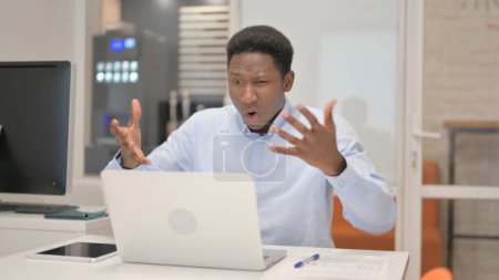 Téléchargez les photos : Homme d'affaires africain choqué par la perte sur ordinateur portable au bureau - en image libre de droit