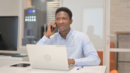 Téléchargez les photos : Un homme d'affaires africain parle au téléphone avec un client - en image libre de droit