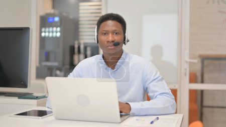 Téléchargez les photos : Homme africain avec casque regardant la caméra dans le centre d'appels - en image libre de droit
