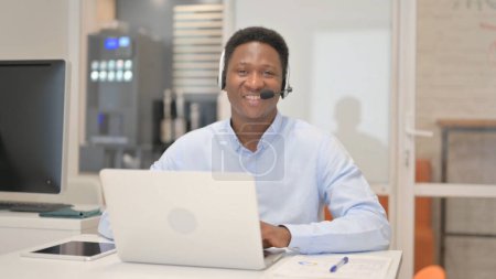 Photo for Smiling African Man with Headset Looking at Camera in Call Center - Royalty Free Image